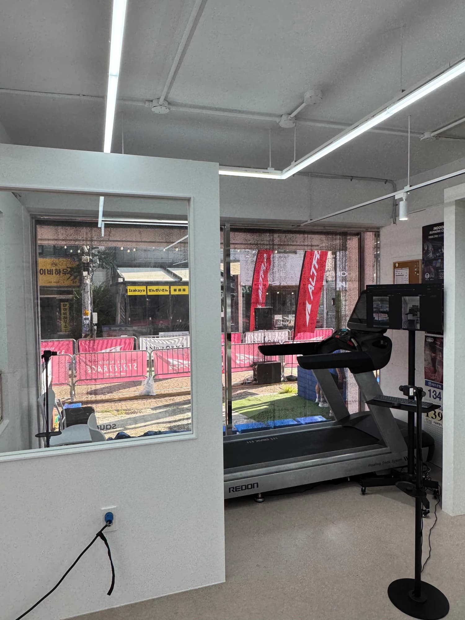An indoor running space with a treadmill and recording cameras by a window