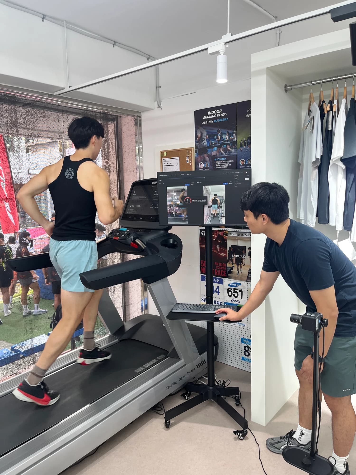 A coach checks side and rear recordings of a runner on a treadmill